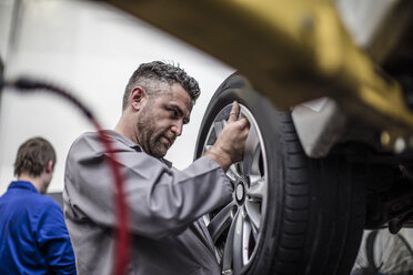 Car mechanic in a workshop changing tire - ZEF10717