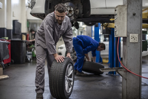 Automechaniker in einer Werkstatt beim Reifenwechsel, lizenzfreies Stockfoto