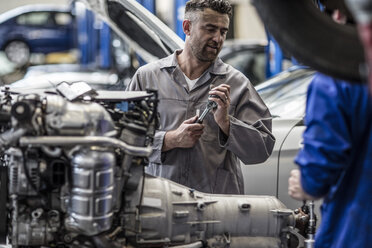 Two car mechanics next to v8 engine in a workshop - ZEF10721