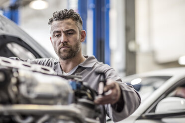 Automechaniker in einer Werkstatt bei Arbeiten am Motor - ZEF10723