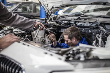 Zwei Automechaniker in einer Werkstatt reparieren gemeinsam ein Auto - ZEF10724