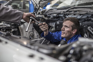 Zwei Automechaniker in einer Werkstatt reparieren gemeinsam ein Auto - ZEF10725