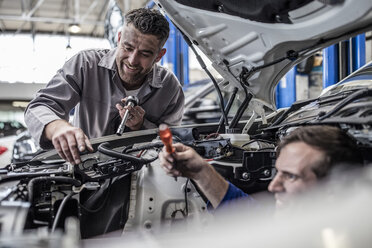 Zwei Automechaniker in einer Werkstatt reparieren gemeinsam ein Auto - ZEF10726