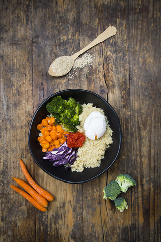 Lunch bowl of quinoa, red cabbage, carrots, roasted chickpeas, broccoli, poached egg and ajvar stock photo