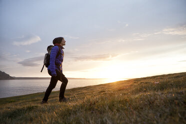 Island, Frau beim Wandern in der Dämmerung auf einem Hügel - RBF05212