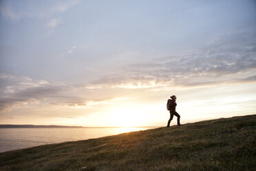 Island, Frau beim Wandern auf einem Hügel in der Dämmerung - RBF05216