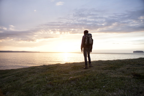 Island, Rückenansicht eines Wanderers mit Blick auf die Aussicht in der Dämmerung, lizenzfreies Stockfoto