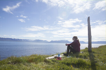 Island, Wanderer ruht sich auf einer Wiese aus und betrachtet die Aussicht - RBF05220