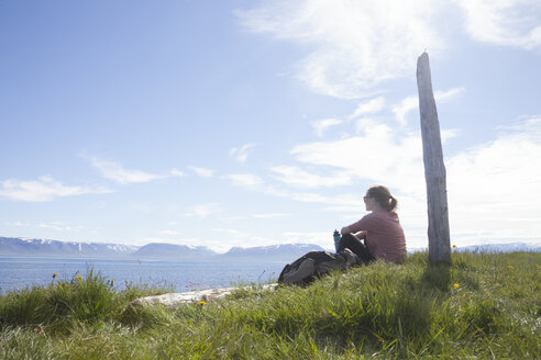 Island, Wanderer ruht sich auf einer Wiese aus und betrachtet die Aussicht - RBF05225