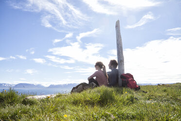 Iceland, hiking couple resting on a meadow looking at view - RBF05226