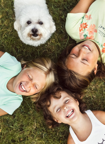 Drei glückliche Mädchen und ein Welpe auf einer Wiese, lizenzfreies Stockfoto