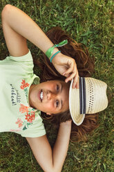 Porträt eines Mädchens mit Strohhut auf einer Wiese liegend - MGOF02556