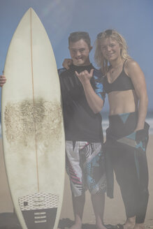 Teenage boy with down syndrome and woman with surfboard on beach - ZEF10867