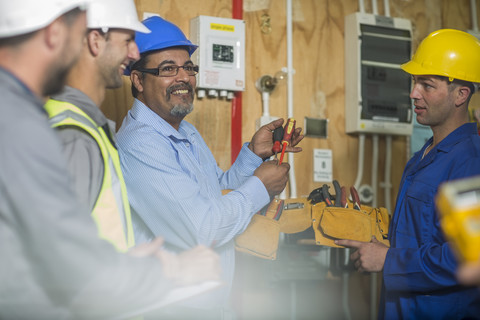 Ausbilder eines Elektrikers erklärt Studenten die Werkzeuge, lizenzfreies Stockfoto