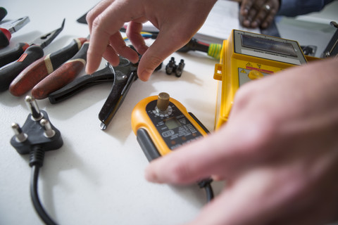 Hände und Tisch mit Elektrikerwerkzeug, lizenzfreies Stockfoto