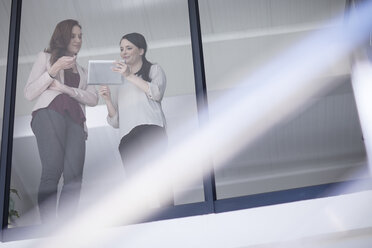 Two businesswomen discussing and looking at digital tablet - ZEF10946