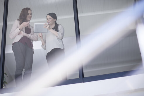 Zwei Geschäftsfrauen im Gespräch und mit Blick auf das digitale Tablet - ZEF10946