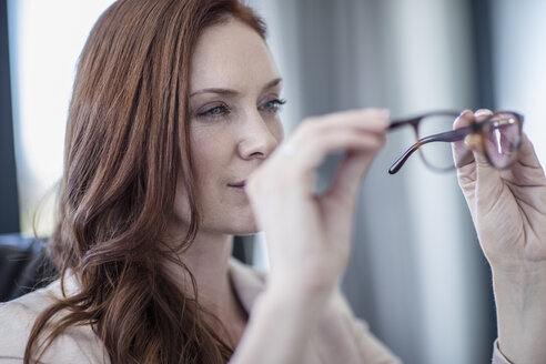 Geschäftsfrau schaut auf ihre Brille - ZEF10956