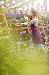 Frau, die in einem Gartenzentrum Pflanzentöpfe auf einen Ständer stellt - ZEF10987