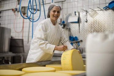 Arbeiter in einer Käsefabrik beim Etikettieren eines Käselaibs - ZEF11012