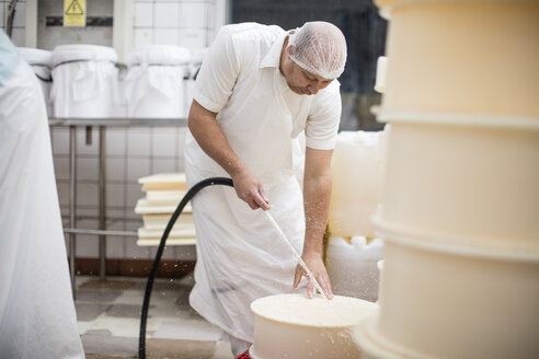 Arbeiter in einer Käsefabrik reinigt Behälter mit einem Schlauch - ZEF11017