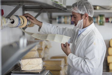 Arbeiter in einer Käsefabrik wiegt verpackten Käse - ZEF11047