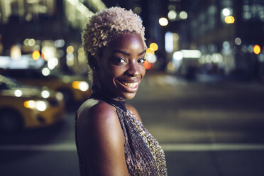 USA, New York City, Porträt einer glücklichen jungen Frau auf dem Times Square bei Nacht - GIOF01566