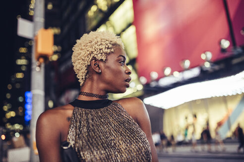 USA, New York City, junge Frau auf dem Times Square bei Nacht, die etwas beobachtet - GIOF01572