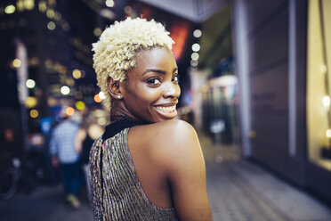 USA, New York City, smiling young woman on Times Square at night - GIOF01573