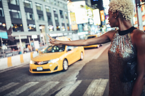 USA, New York City, junge Frau, die nachts auf dem Times Square ein Taxi ruft - GIOF01580