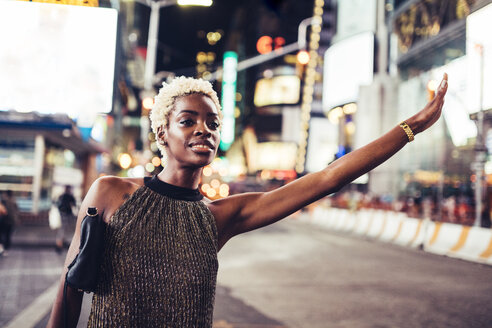 USA, New York City, junge Frau, die nachts auf dem Times Square ein Taxi ruft - GIOF01581