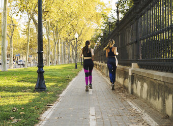 Zwei junge Frauen joggen auf dem Bürgersteig - EBSF01783