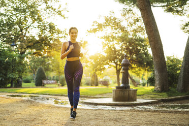 Young woman jogging in park at sunset - EBSF01814