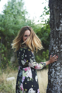 Smiling blond woman wearing dress with floral design - JCF00063