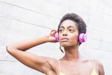 Porträt einer Frau, die mit rosa Kopfhörern Musik hört - SIPF00970