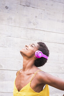 Glückliche Frau hört Musik mit rosa Kopfhörern - SIPF00971