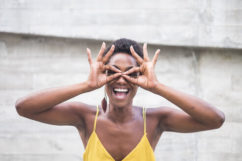 Laughing woman forming spectacles with fingers - SIPF00976