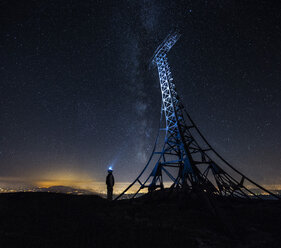 Italien, Marken, Silhouette eines Mannes mit Stirnlampe, der das Gipfelkreuz des Monte Catria bei Nacht betrachtet - LOMF00439