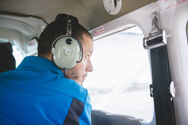 Mann mit Kopfhörern im Leichtflugzeug schaut aus dem Fenster - GEMF01179