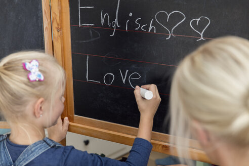 Mutter beobachtet ihre Tochter beim Schreiben des Wortes 