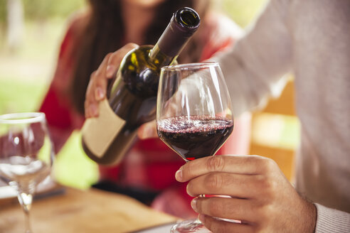 Man pouring red wine into glass - ZEDF00377