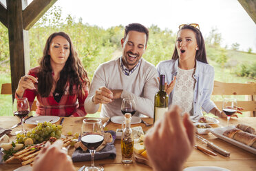 Freunde beim geselligen Beisammensein am Tisch im Freien mit Rotwein und kaltem Snack - ZEDF00390