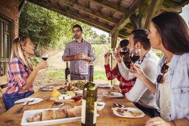 Man giving a speech at outdoor table watched by friends - ZEDF00400