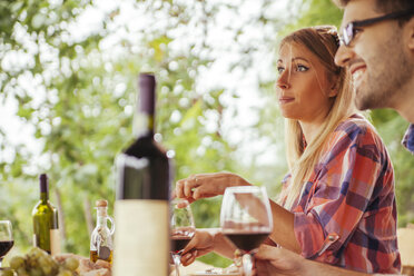 Couple having red wine at outdoor table - ZEDF00405