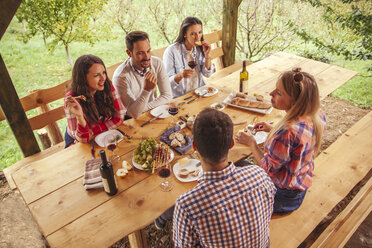 Friends socializing at outdoor table with red wine and cold snack - ZEDF00407