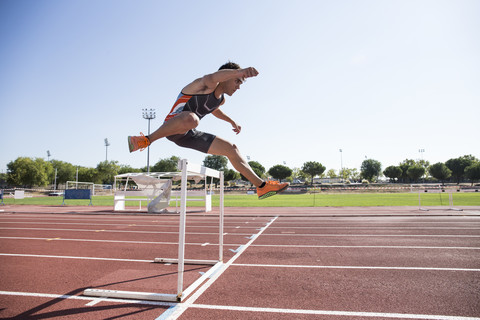 Athlete clearing hurdle during a race stock photo