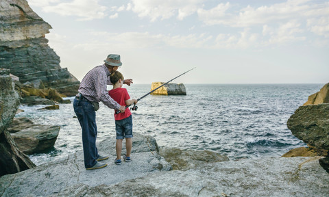 Grandfather and grandson fishing together at the sea stock photo