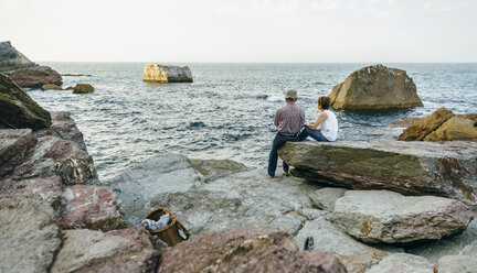 Senior couple fishing at the sea sitting on rock - DAPF00435
