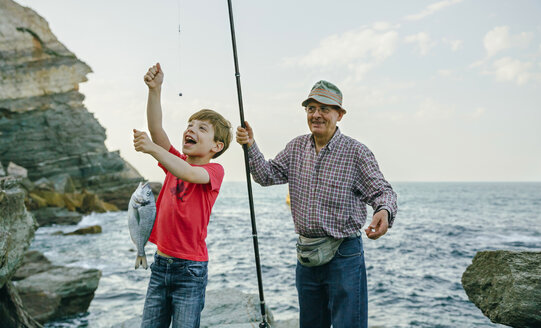 Happy boy holding fish on fishing line caught by his grandfather - DAPF00438