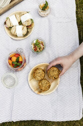 Hand taking muffin from picnic blanket with vegetarian snacks - EVGF03107